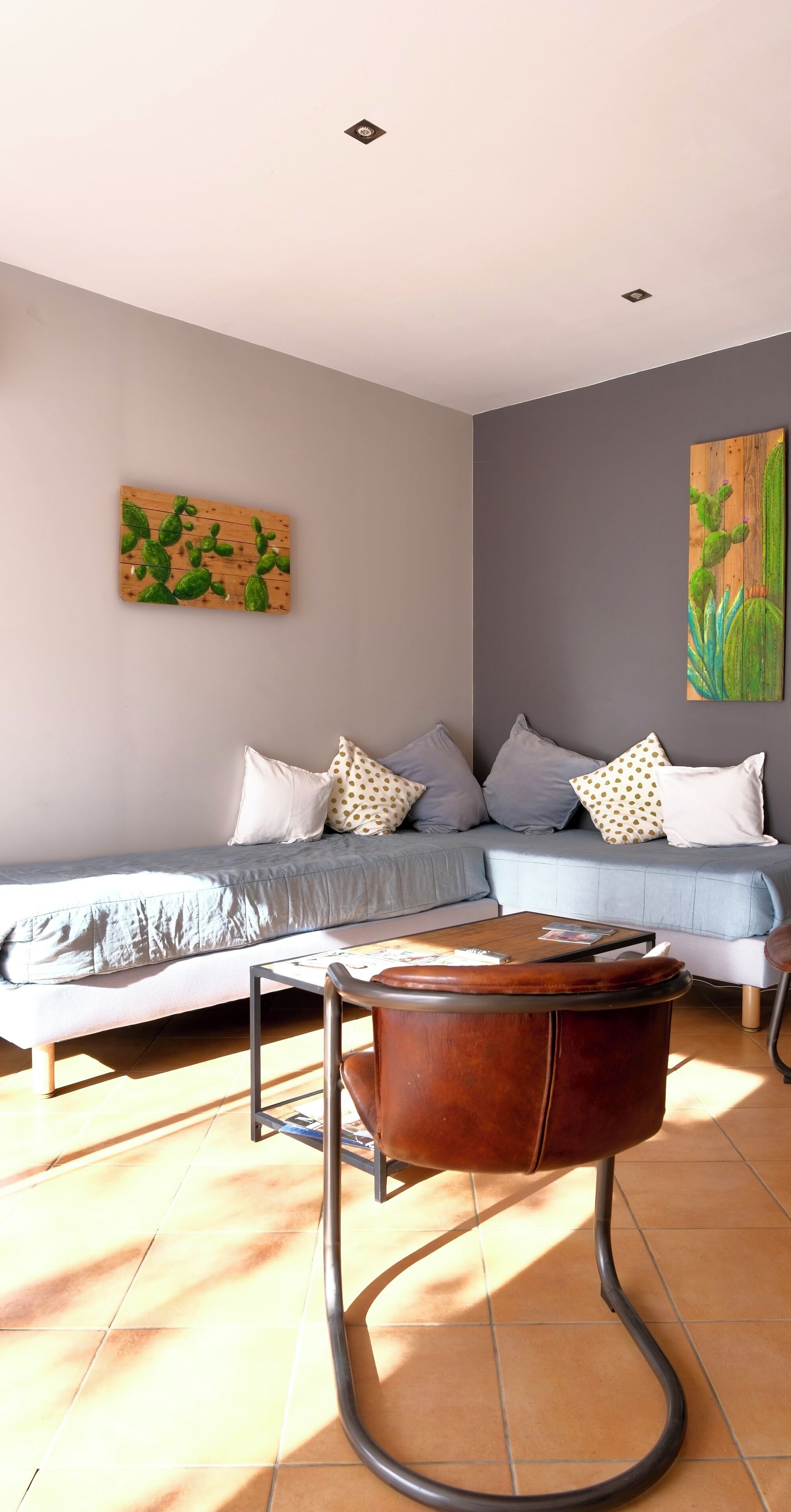Un salon moderne avec un canapé gris, des coussins à motifs et une table basse en bois.
