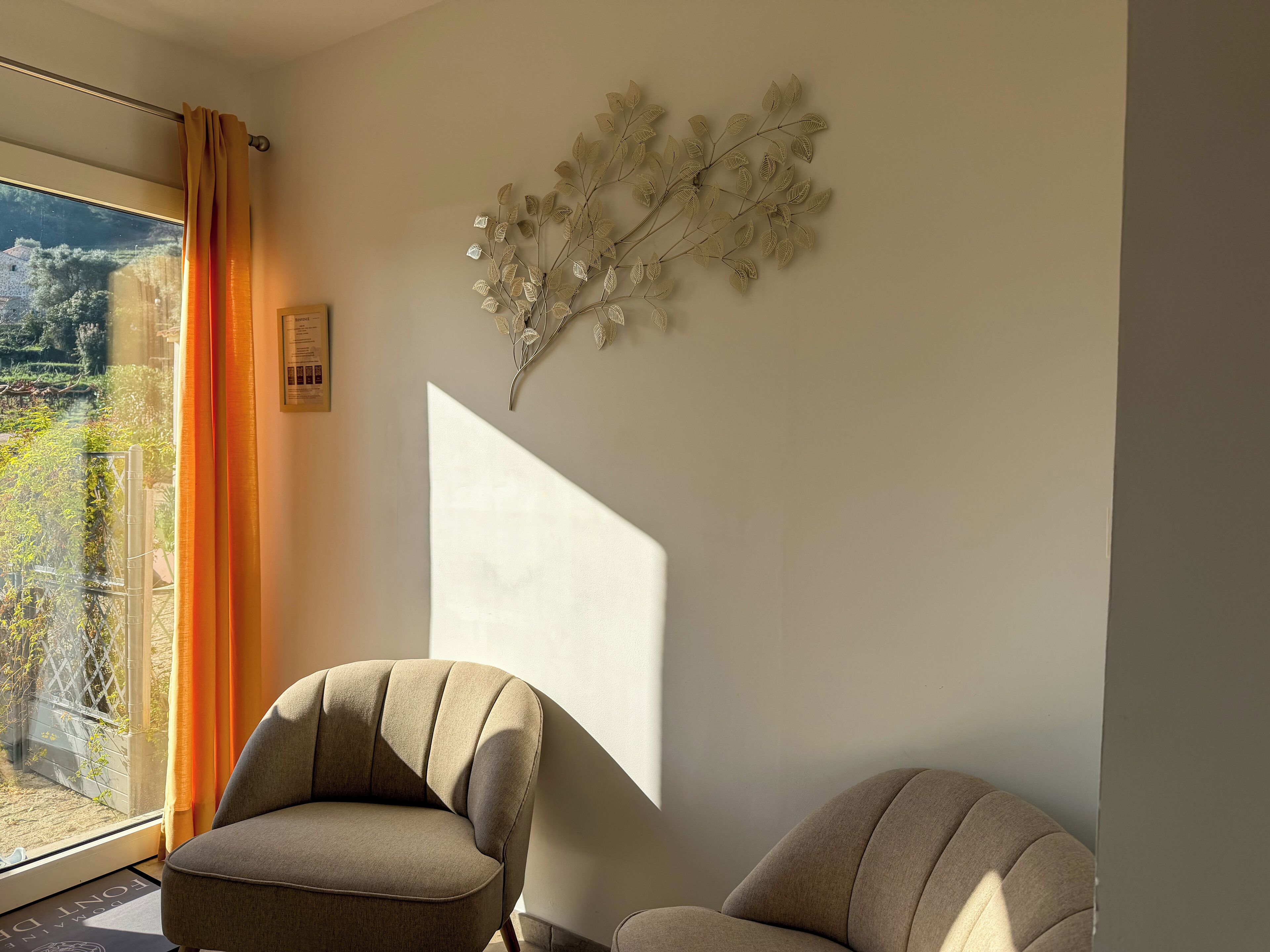 Een moderne kamer met een groot raam, een bank en een decoratief wandobject.