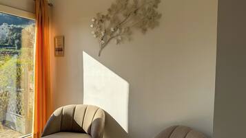 Een moderne kamer met een groot raam, een bank en een decoratief wandobject.