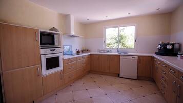 A kitchen with wooden cabinets, a microwave, an oven, a dishwasher, and a window providing natural light.