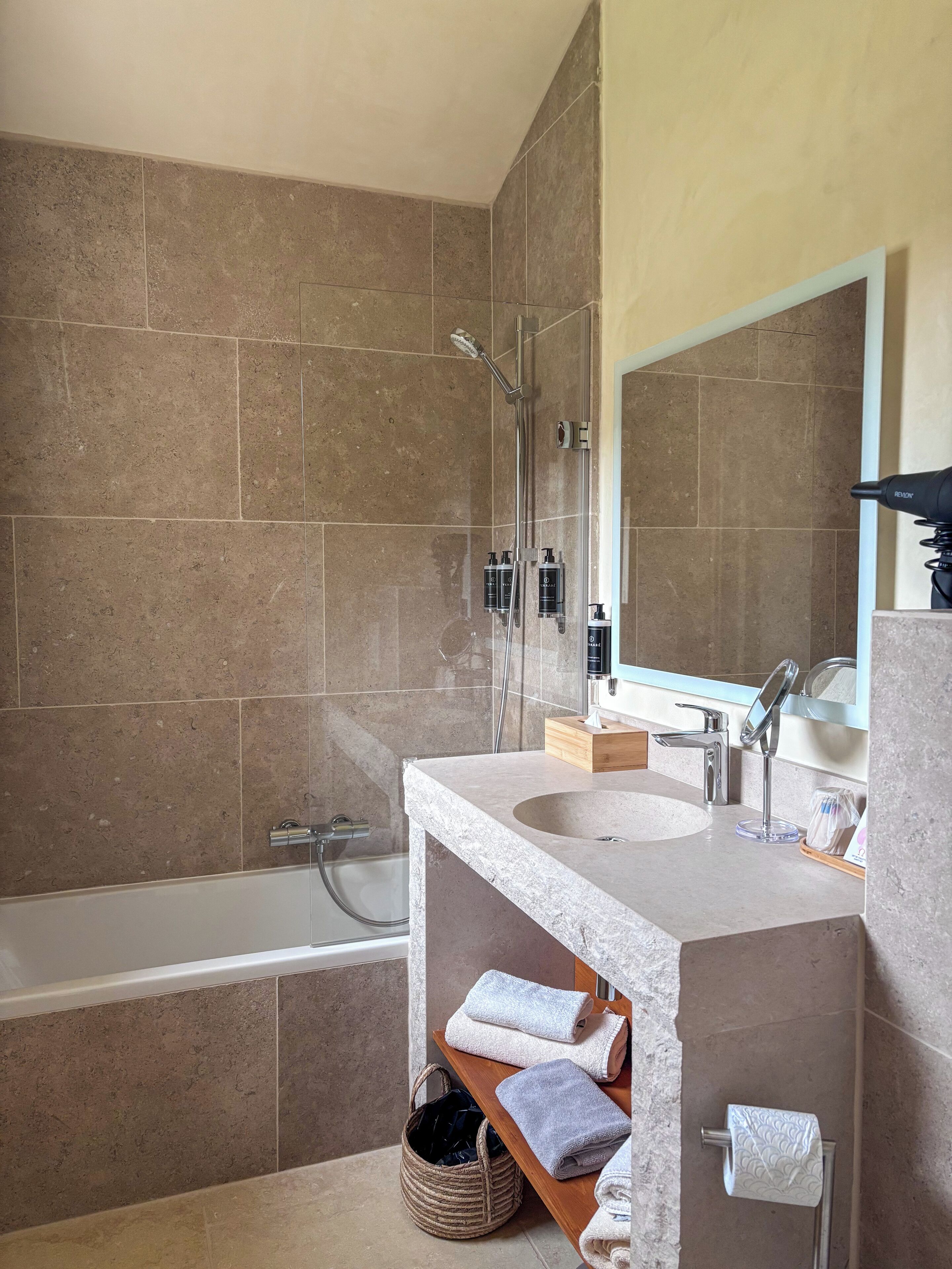 A modern bathroom with a bathtub, a sink with a mirror, and a shower area.