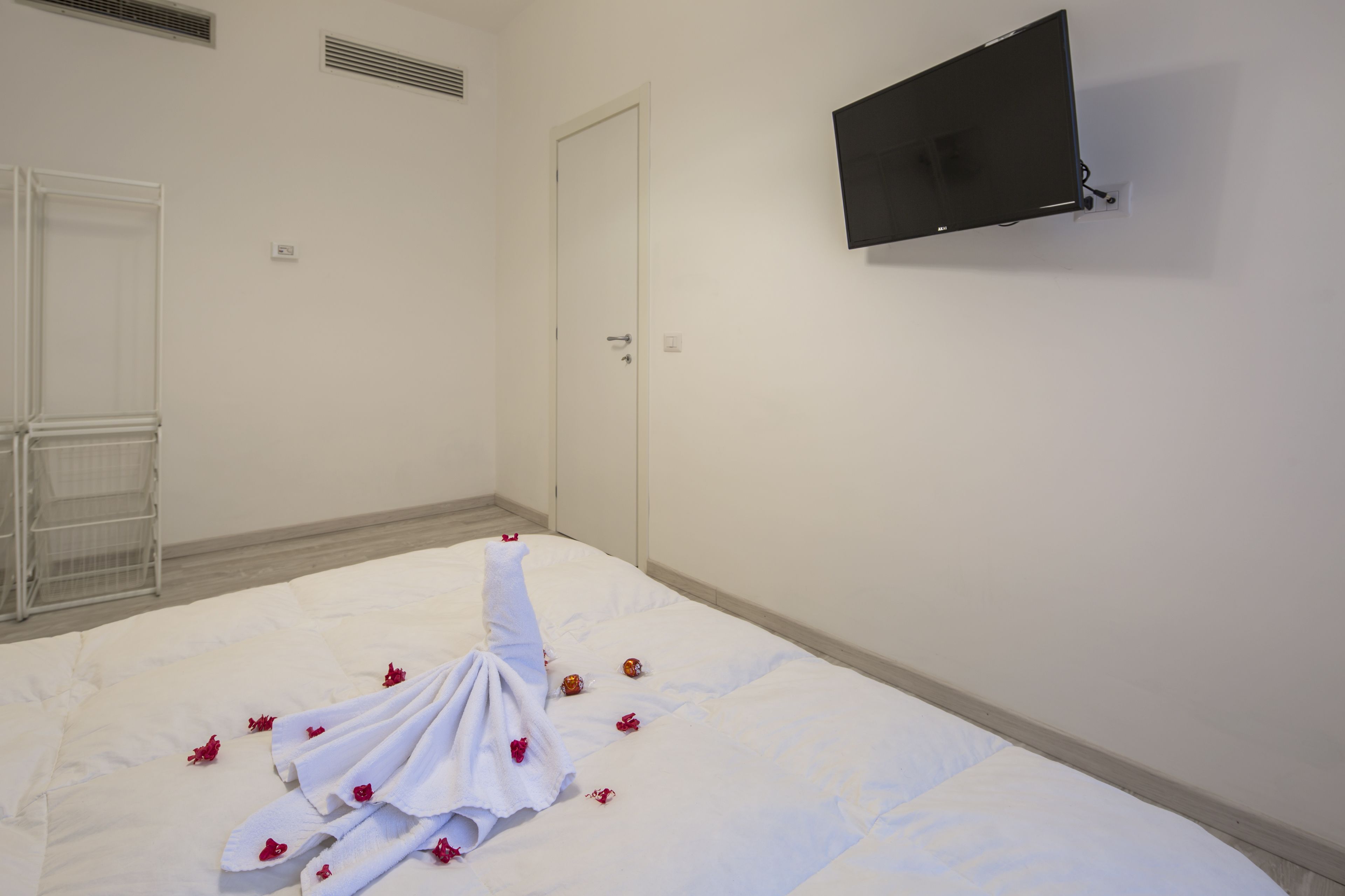 A hotel room with a bed, a TV mounted on the wall, and a door.