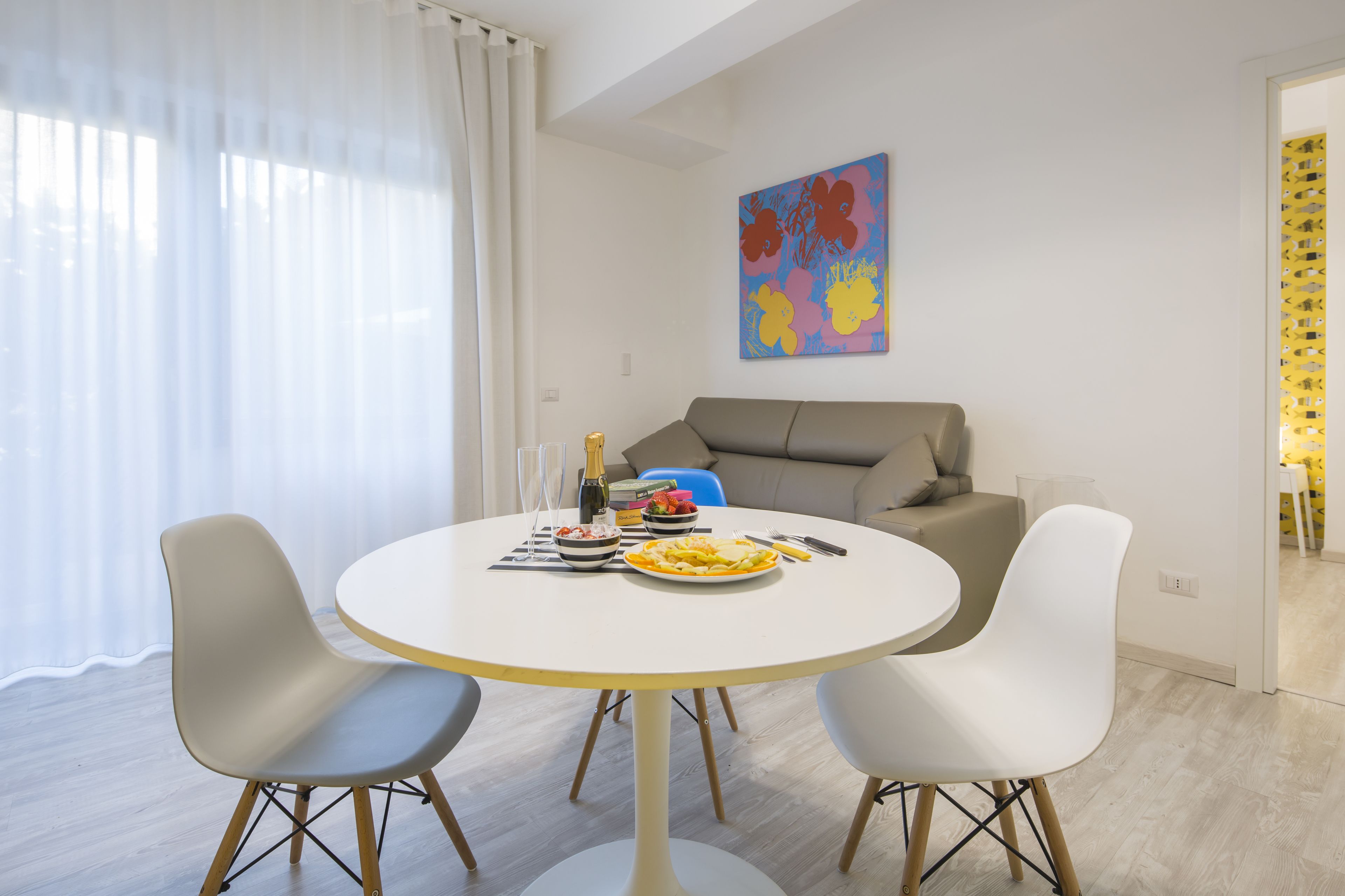 A modern dining area with a round table, two chairs, and a sofa in the background.