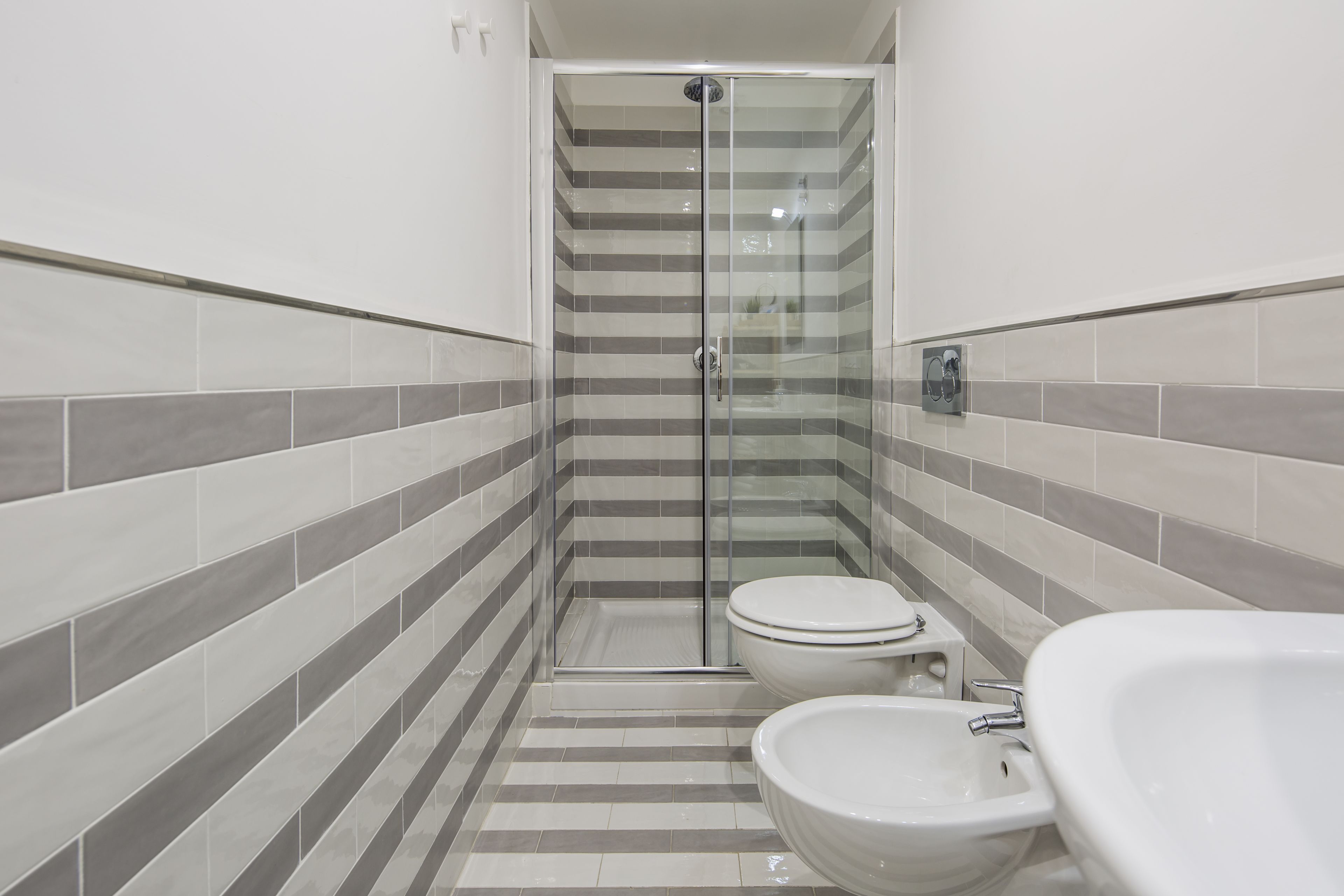 Un baño con ducha, inodoro y dos lavamanos.