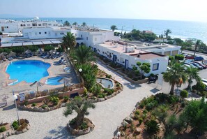 A hotel with a pool area, palm trees, and a view of the sea. - Hotel el Puntazo II (Mojacar)