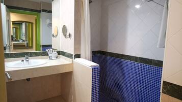 Un baño con lavamanos blanco, espejo y ducha con azulejos azules.
