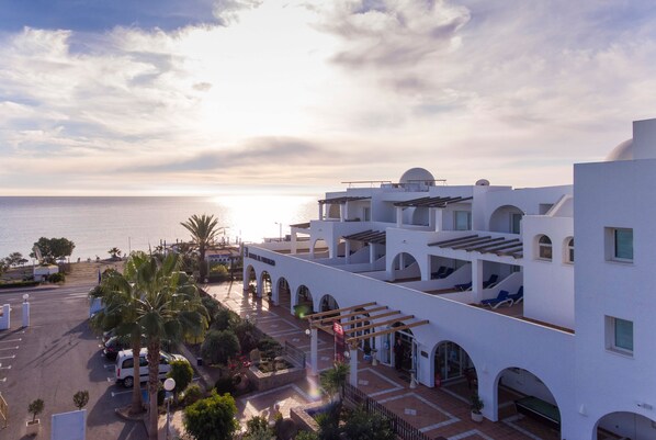 A coastal hotel with a rooftop terrace, palm trees, and a view of the sea. - Hotel el Puntazo II (Mojacar)