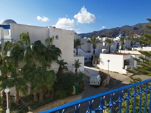 A residential area with white buildings, palm trees, and a mountainous backdrop. - Hotel el Puntazo II (Mojacar)