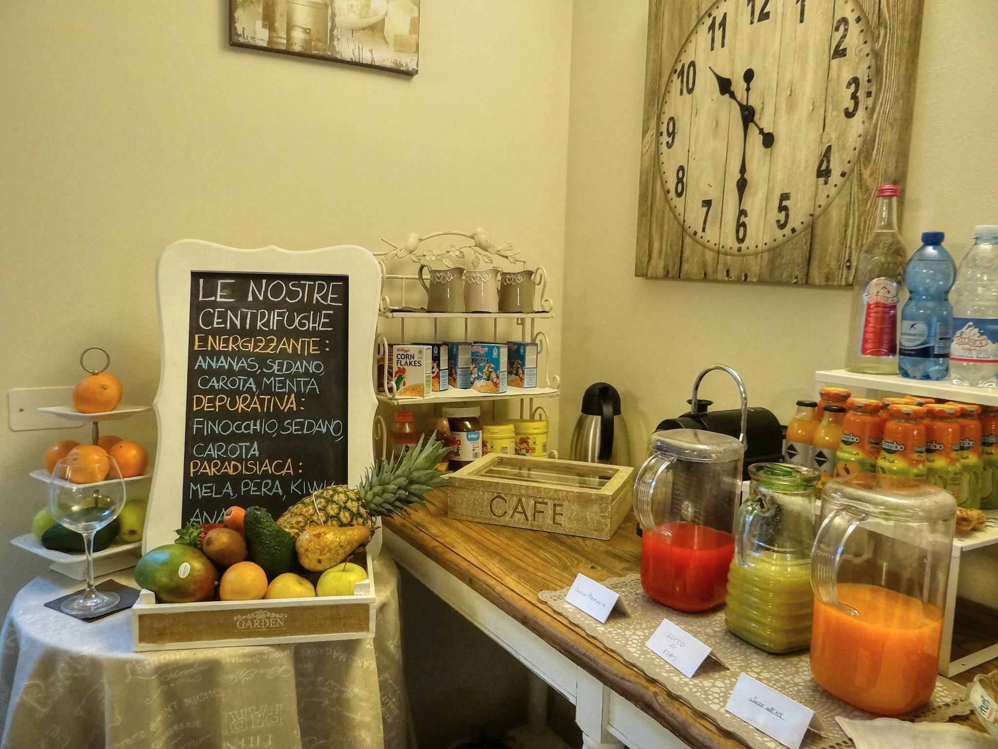 A breakfast area with a chalkboard menu listing food items, a clock, and various breakfast beverages.