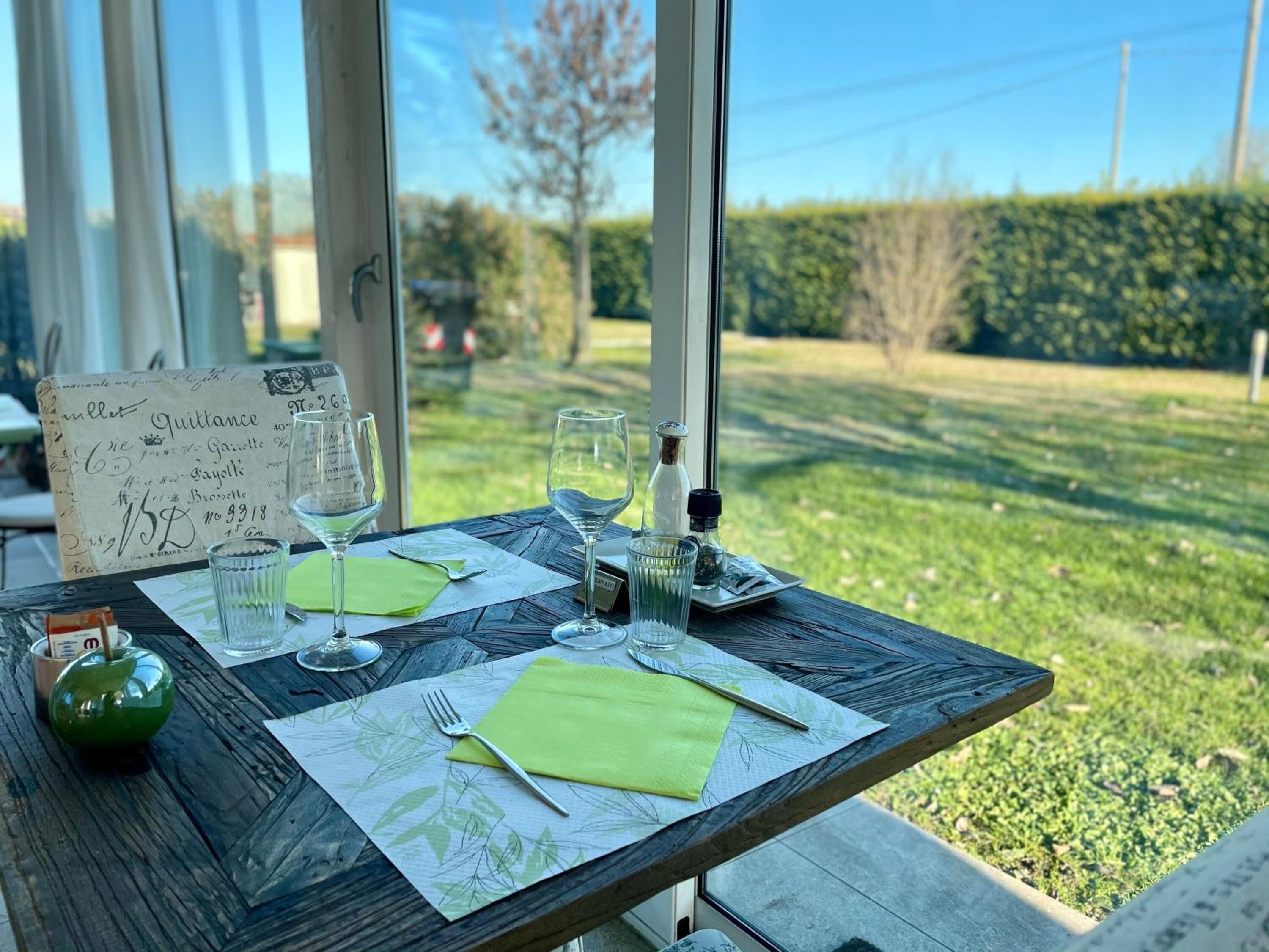 Mesa lista para dos con copas de vino, una botella y un menú.