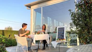 A couple dining at an outdoor table with a menu board in the background.