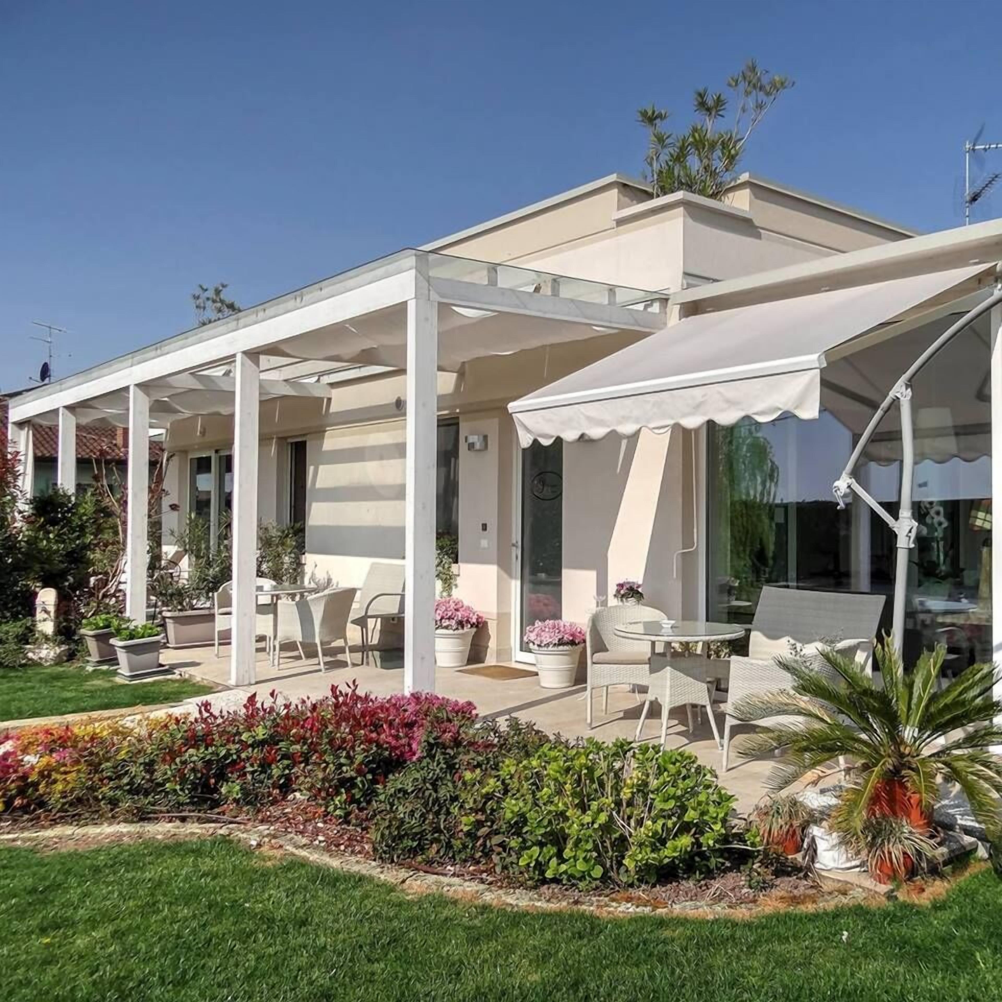 A modern house with a covered patio area featuring outdoor furniture and potted plants.