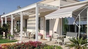A modern house with a covered patio area featuring outdoor furniture and potted plants.