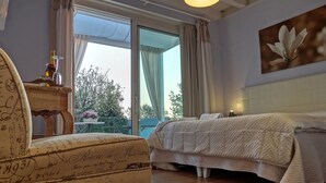 Una camera da letto con un letto, una sedia, un tavolo con una bottiglia e un quadro.