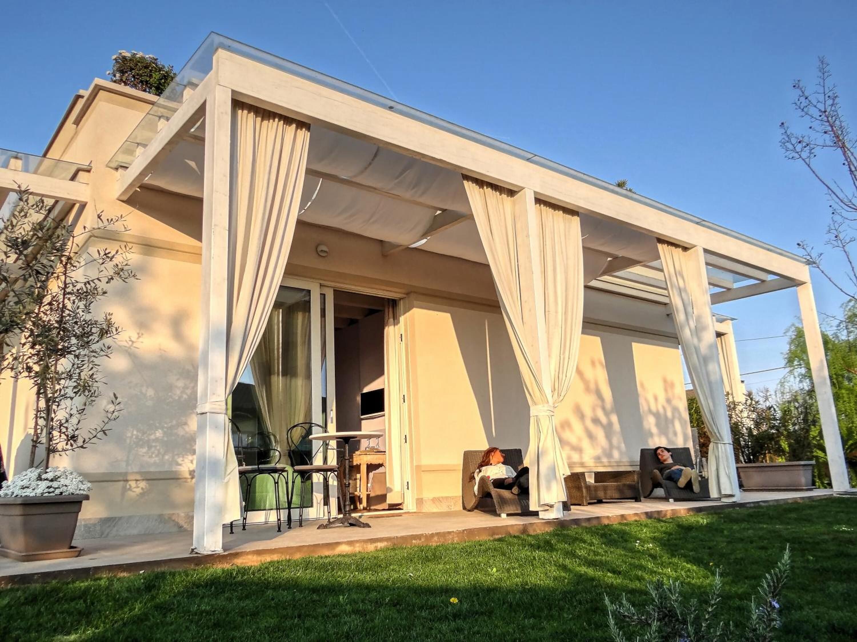 Ein modernes Haus mit überdachter Terrasse, Gartenmöbeln und einem gepflegten Rasen.