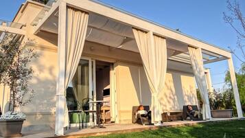 Ein modernes Haus mit überdachter Terrasse, Gartenmöbeln und einem gepflegten Rasen.