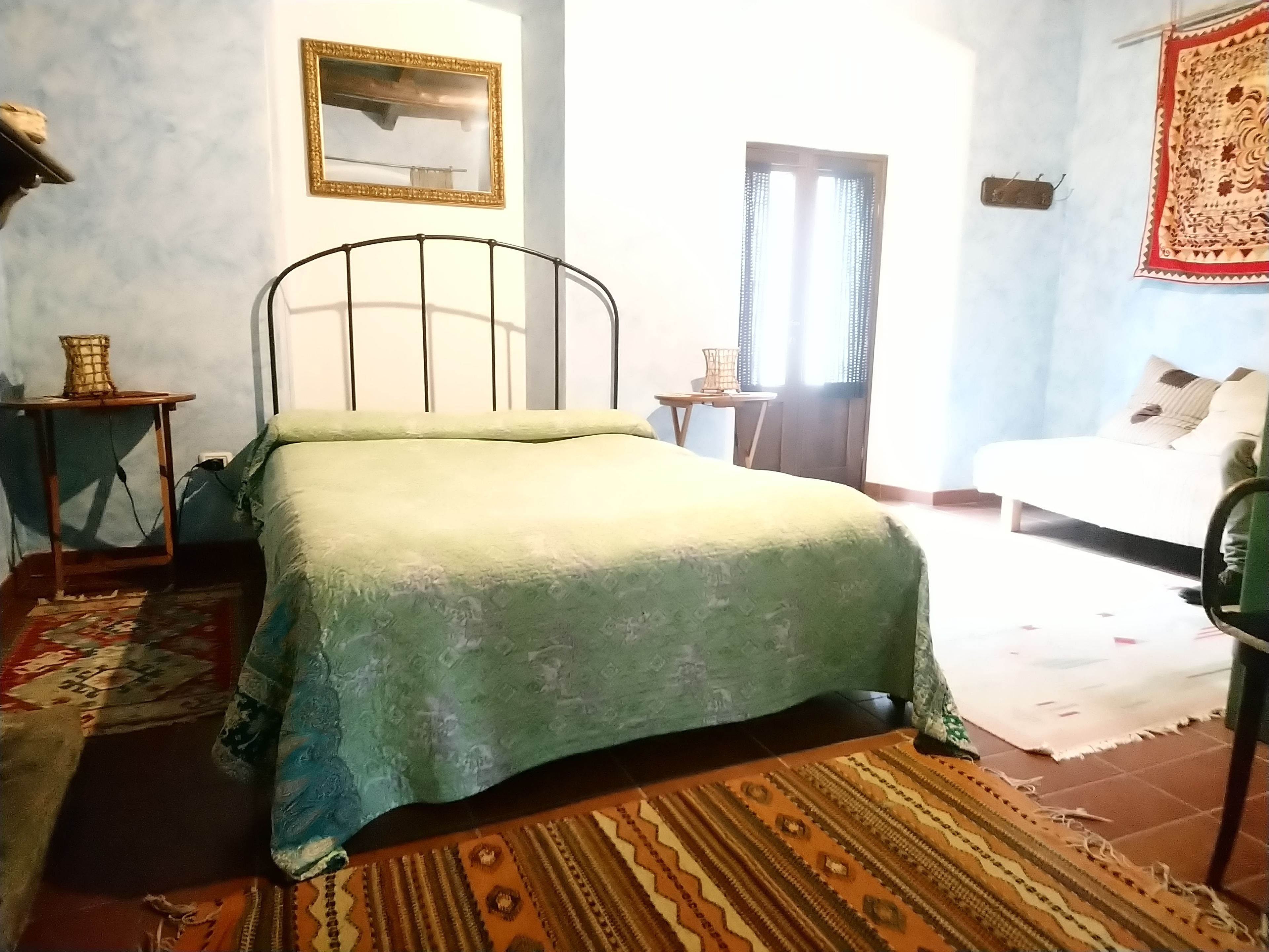 Une chambre à coucher comprenant un lit, une petite table, une chaise, une fenêtre avec des rideaux et un cadre photo fixé au mur.