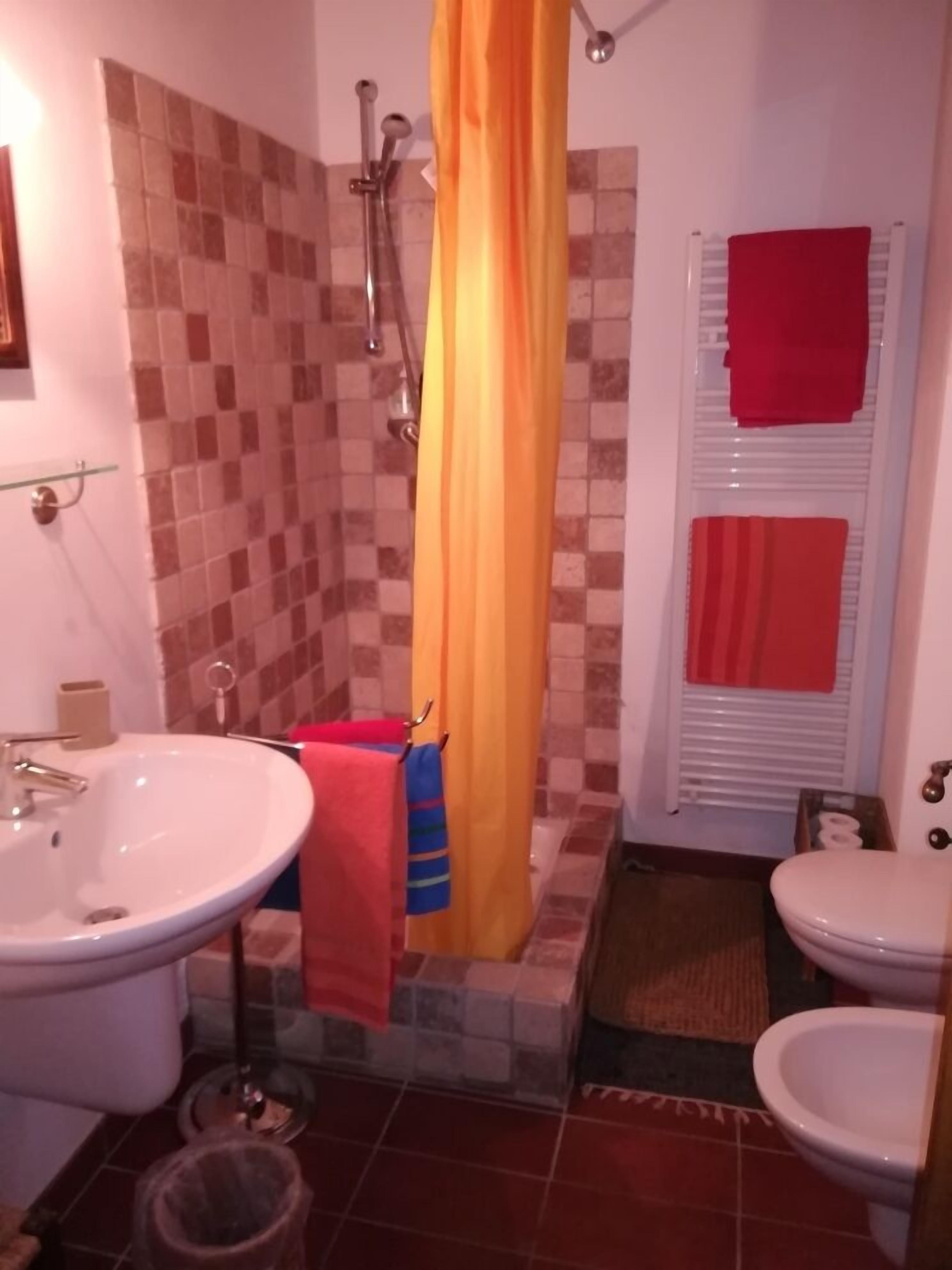 A bathroom with a shower, two toilets, a sink, and a tiled floor.