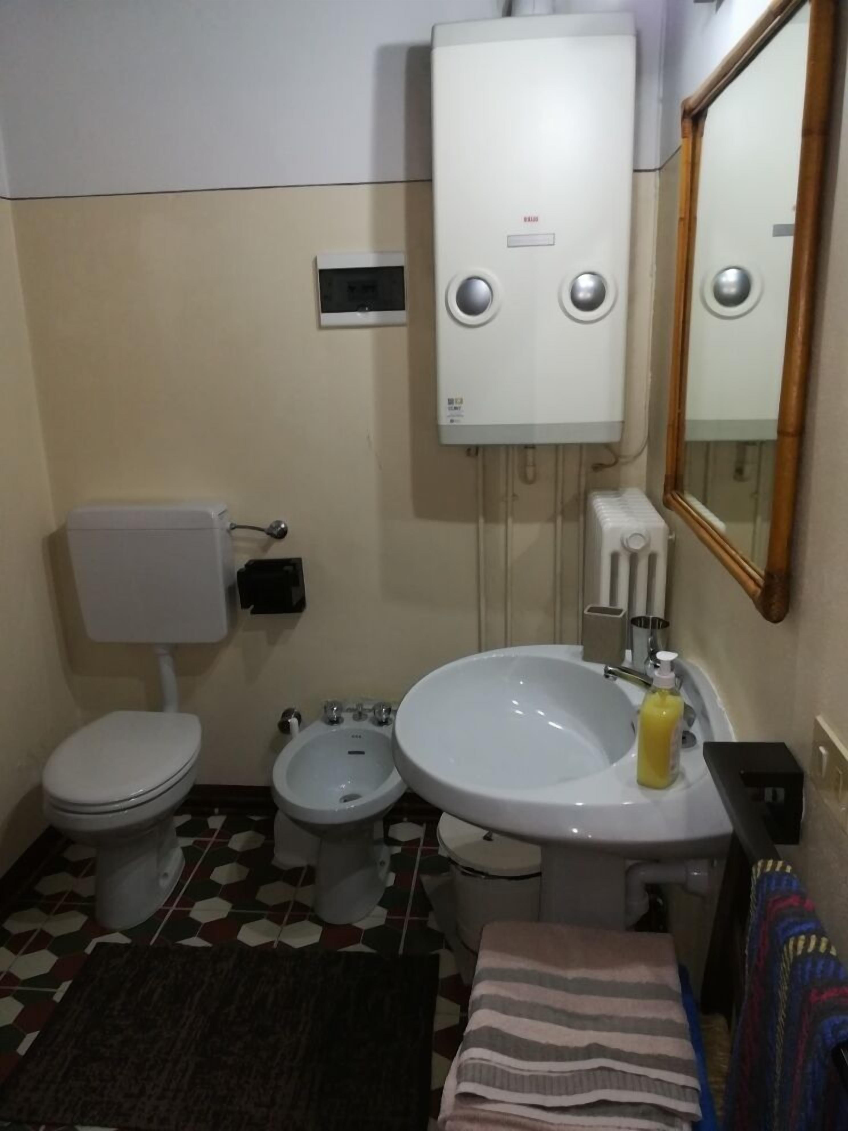 A small bathroom with a toilet, bidet, sink, and a mirror.
