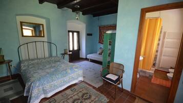 A bedroom with a bed, a chair, a window, and a door leading to a bathroom.
