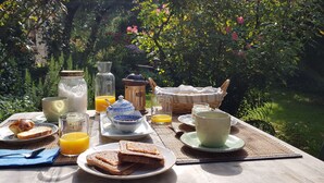 Un esmorzar preparat amb torrades, suc i una cafetera damunt una taula a l'exterior.