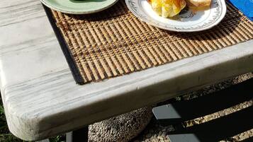 A breakfast table set outdoors with a variety of food items, including toast, eggs, and juice.