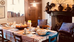 Una menjador rústic amb una taula de fusta preparada per l'esmorzar, una llar de foc i vista al camp.