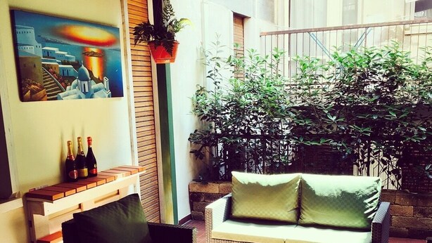 A cozy outdoor seating area with wicker furniture, a small table, and a potted plant. - La Giara Rooms (Verona)