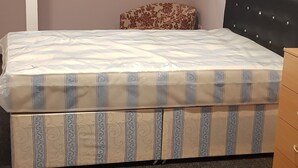 A bedroom with a bed, a small bench, a headboard, and a window with blinds. - Ranmoor Lodge (Sheffield)