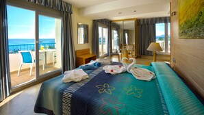 A hotel room with a balcony, a bed with a floral bedspread, a desk with a chair, and a view of the sea. - Hotel Punta del Cantal  (Mojacar)