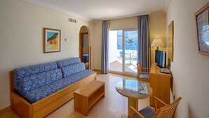 A hotel room with a sofa, a small table, a TV, and a balcony with a view. - Hotel Punta del Cantal  (Mojacar)