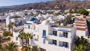 A white building with blue accents, palm trees, and a mountainous backdrop. - Hotel Punta del Cantal  (Mojacar)