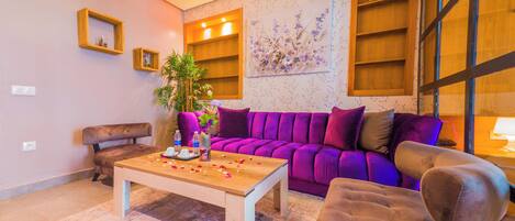 Un salon moderne avec un canapé violet, une table basse en bois et un fauteuil marron.
