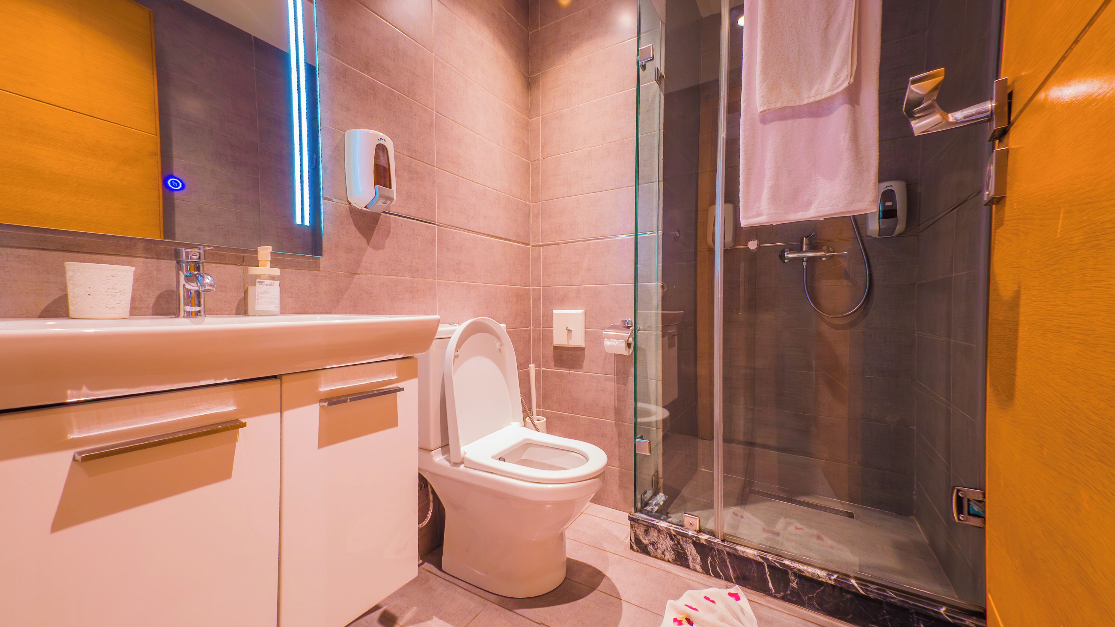 A modern bathroom with a toilet, sink, and glass shower enclosure.