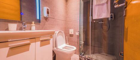 A modern bathroom with a toilet, sink, and glass shower enclosure.