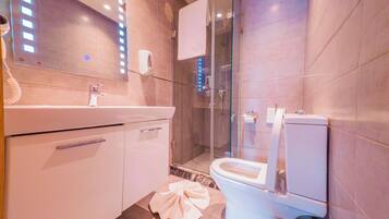 A modern bathroom with a glass shower enclosure, a white toilet, and a vanity with a mirror.