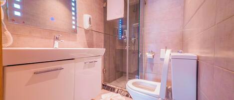 Un bagno moderno con box doccia in vetro, un water bianco e un mobile lavabo con specchio.