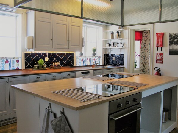 A modern kitchen with a central island, built-in oven, and stainless steel appliances. - STF Jädraås Herrgård - Hostel (Jädraås)