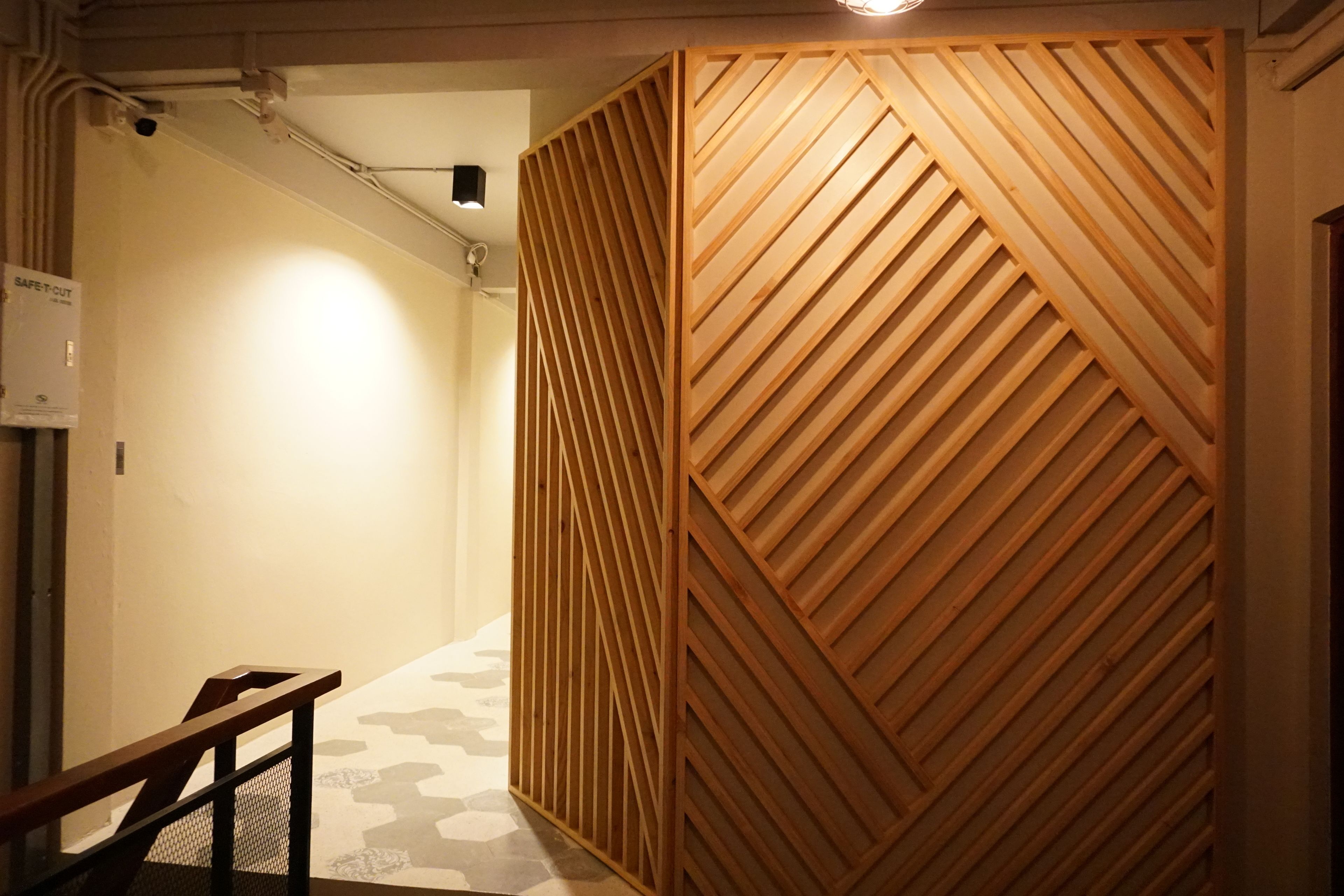 Ein Korridor mit einer Wand aus Holzlatten und einer Treppe mit Metallgeländer.