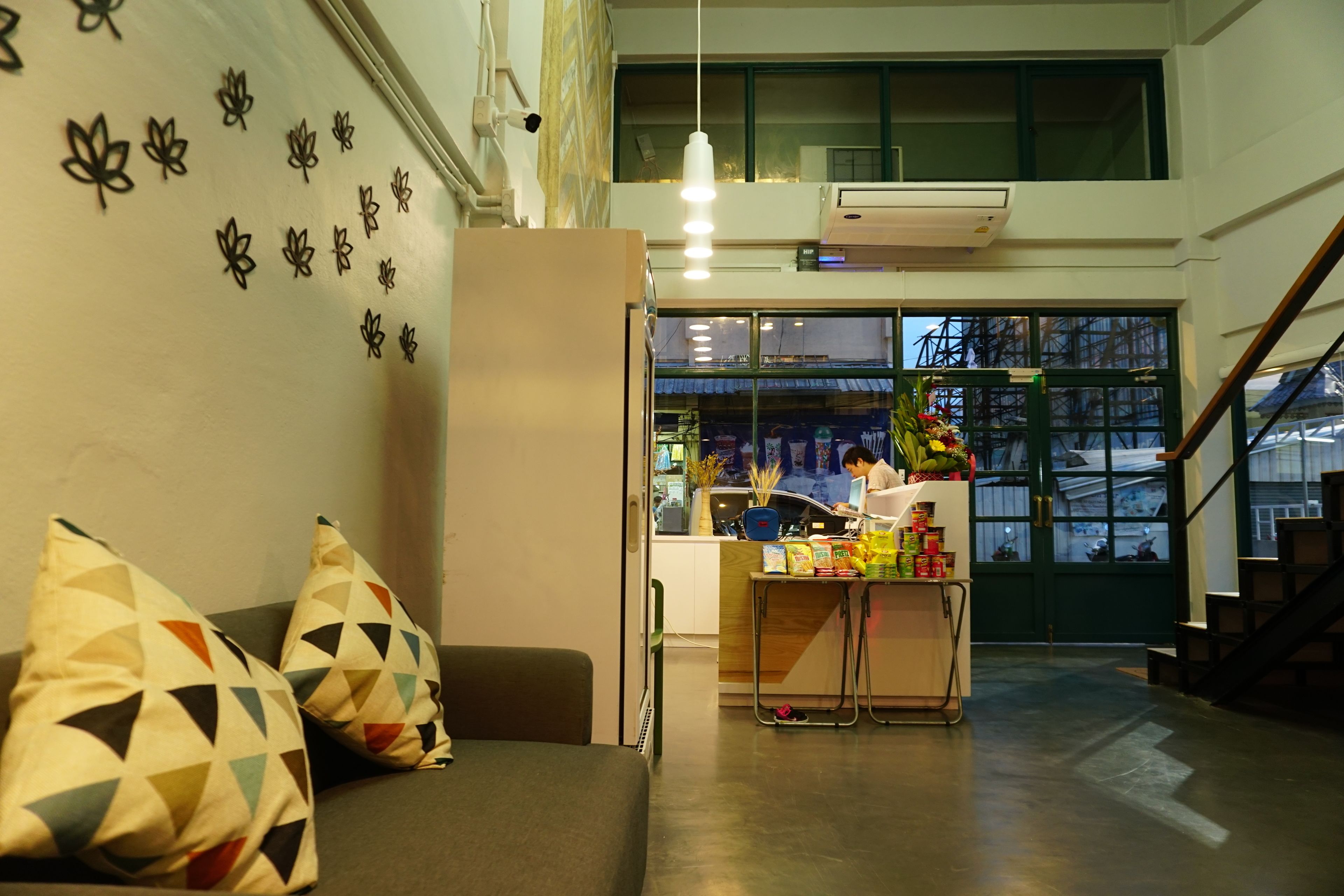 A hotel lobby with a sofa, patterned cushions, a reception desk, and a view of the street outside.