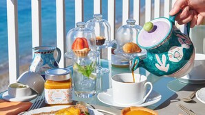 A table set with breakfast items, including toast, strawberries, and a teapot, overlooking a coastal view. - Taverna del Capitano (Massa Lubrense)