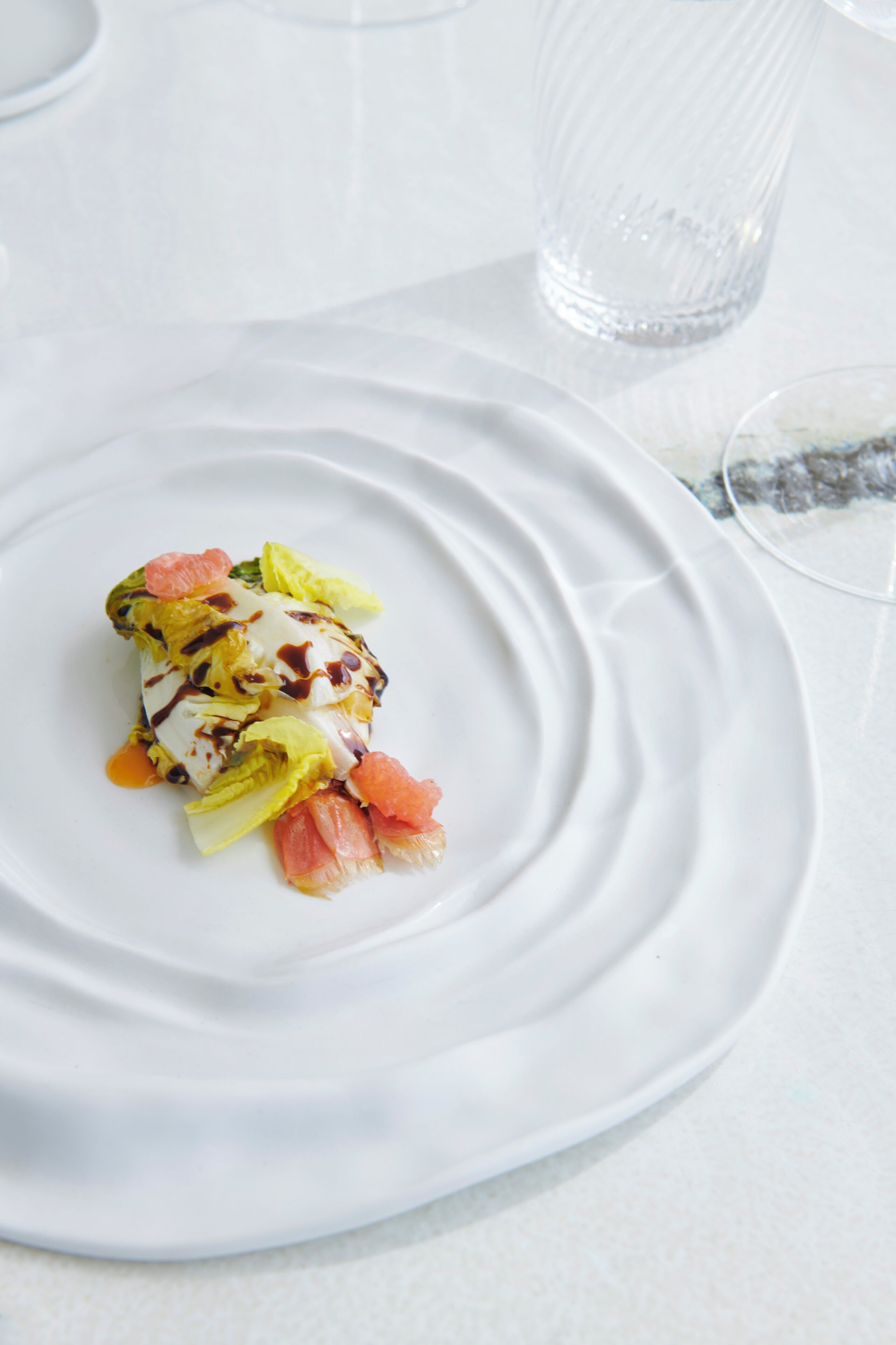 Une assiette blanche avec un dessert, posée sur une table blanche.