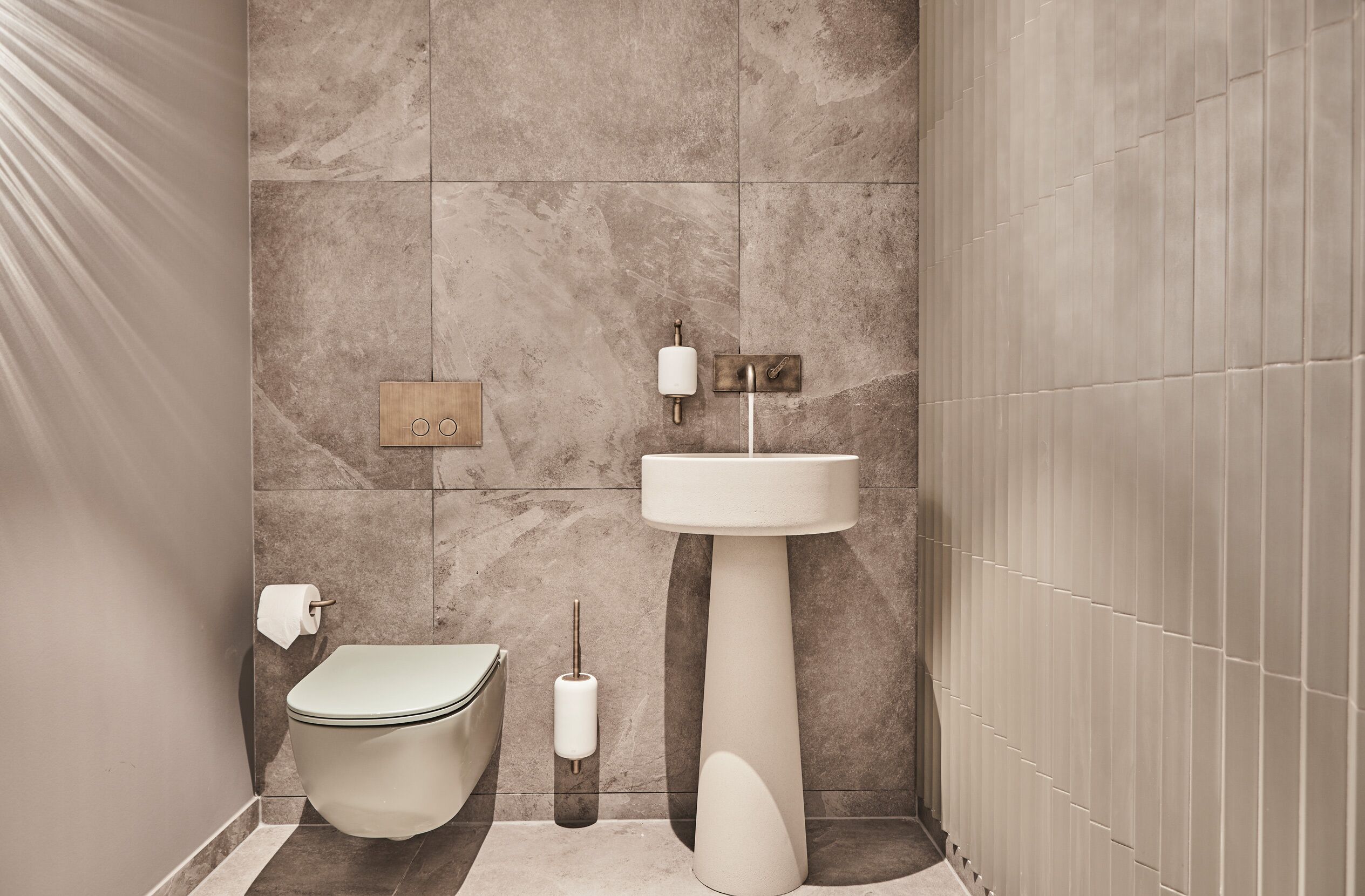 Ein modernes Badezimmer mit Toilette, Waschbecken und Handtuchspender.