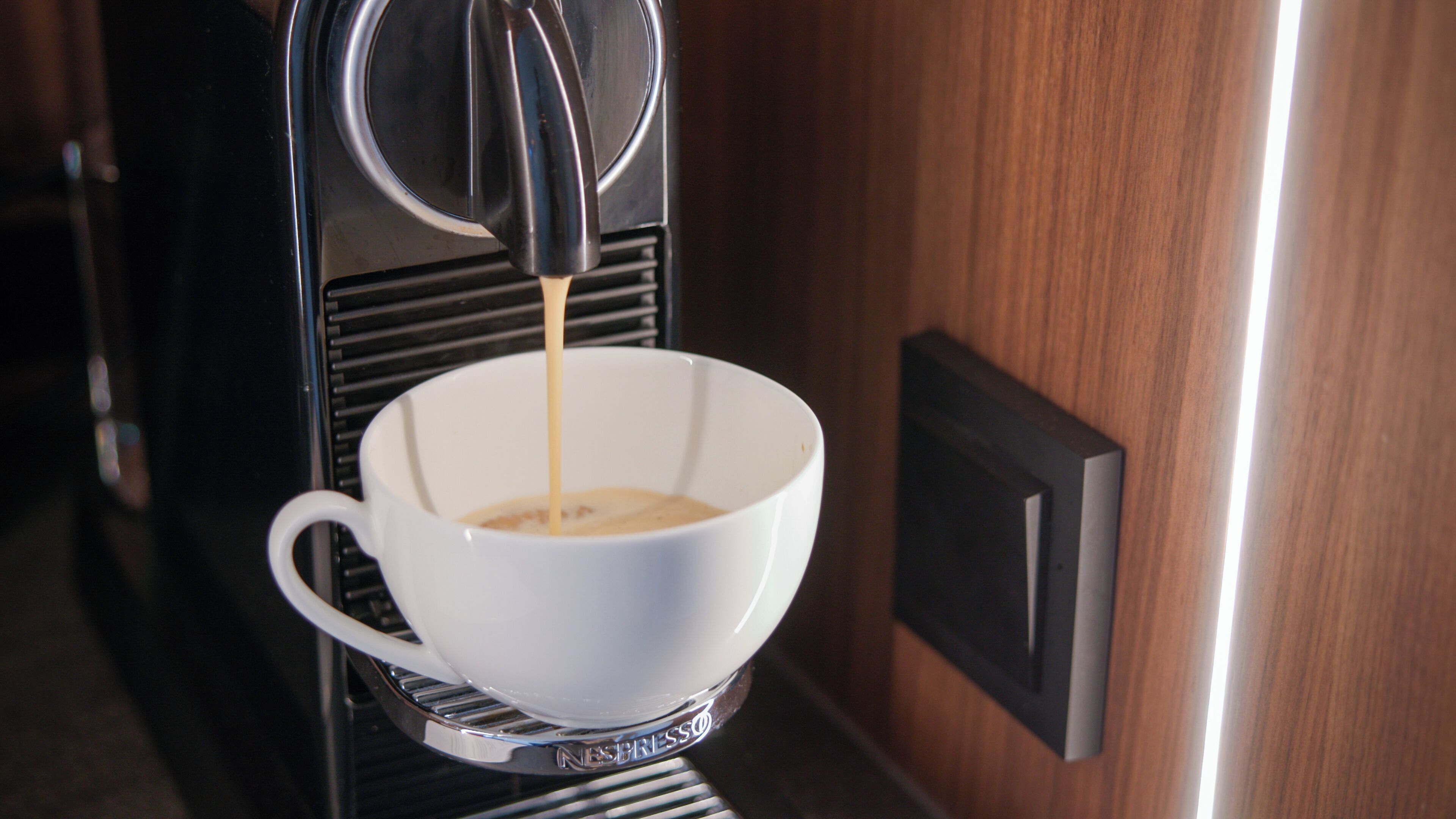 A coffee machine dispensing coffee into a white cup.