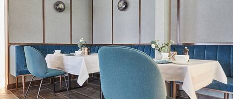 A restaurant with blue upholstered booths, white tablecloths, and a modern interior design.