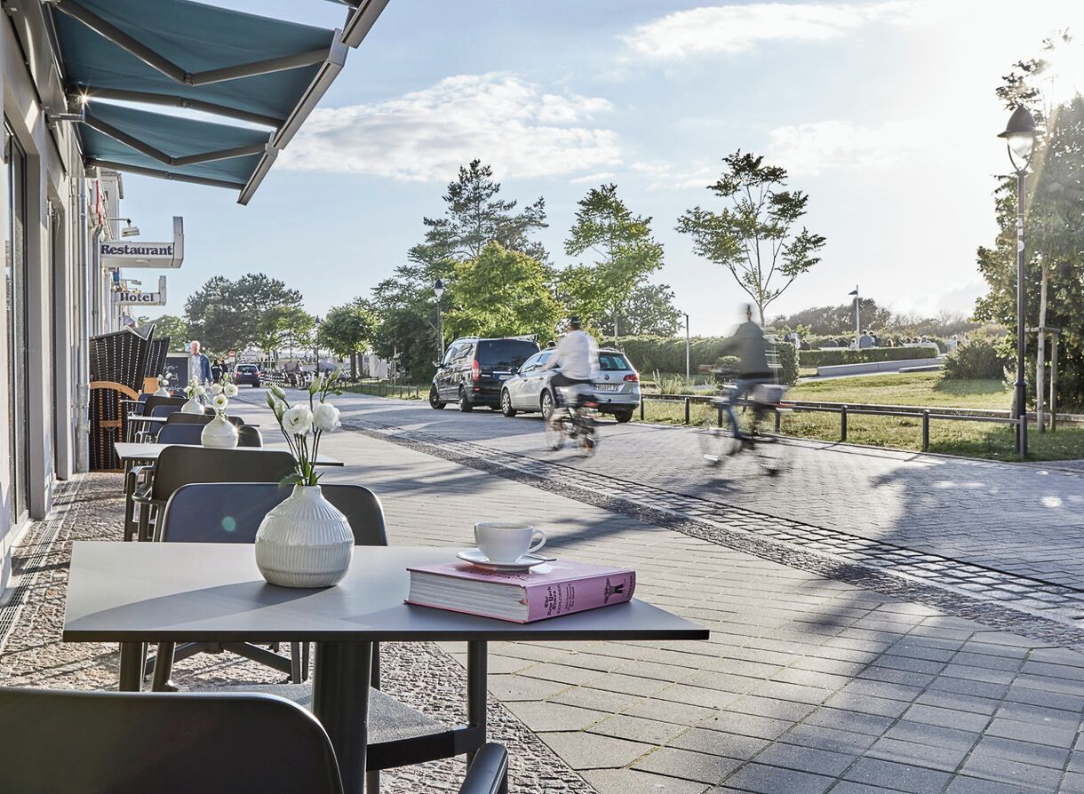 Un café en plein air avec des tables, des chaises et un livre posé sur l’une d’elles.