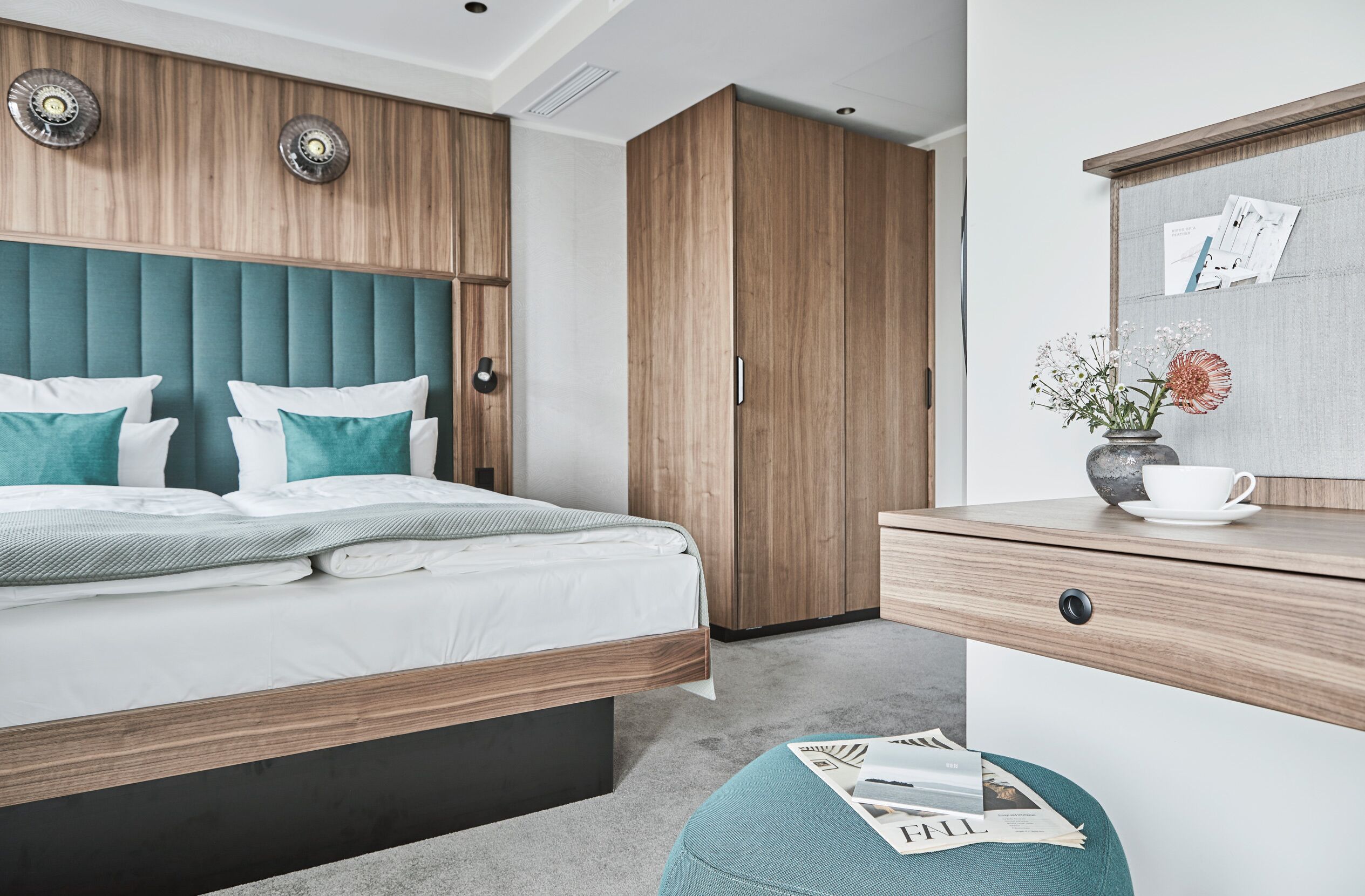 Un dormitorio moderno con una cama, un armario de madera y un escritorio con un florero.