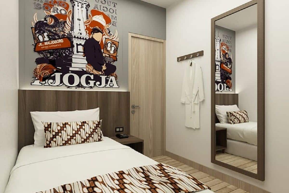 A hotel room with a bed, a nightstand, a mirror, and a poster on the wall.
