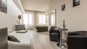 Een moderne hotelkamer met een bed, een zithoek met een tafel, en een grote spiegel.