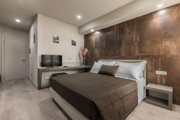 Un dormitorio moderno con una cama grande, televisor y zona de escritorio.